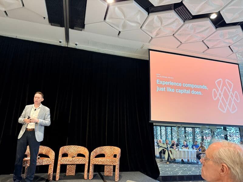 Speaker on stage at PieLab's 2026 Investor Day in Brisbane beside the slide 'Experience compounds, just like capital does'